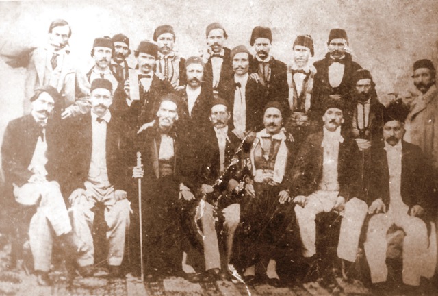 Кожухарският (Кюркчийски) еснаф от Пловдив. В средата (с бастуна) е първомайсторът Пею Кюркчи, вдясно е Никола Кавра, а до него (с носията) е Калчо Дренски. Фотограф: хаджи Никола Кавра, 24 декември 1855 г.